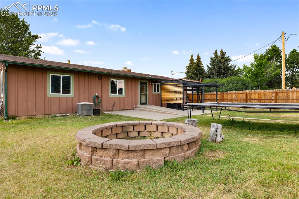 Image 32 of 35: Spacious fenced yard with stone firepit for cozy gatherings