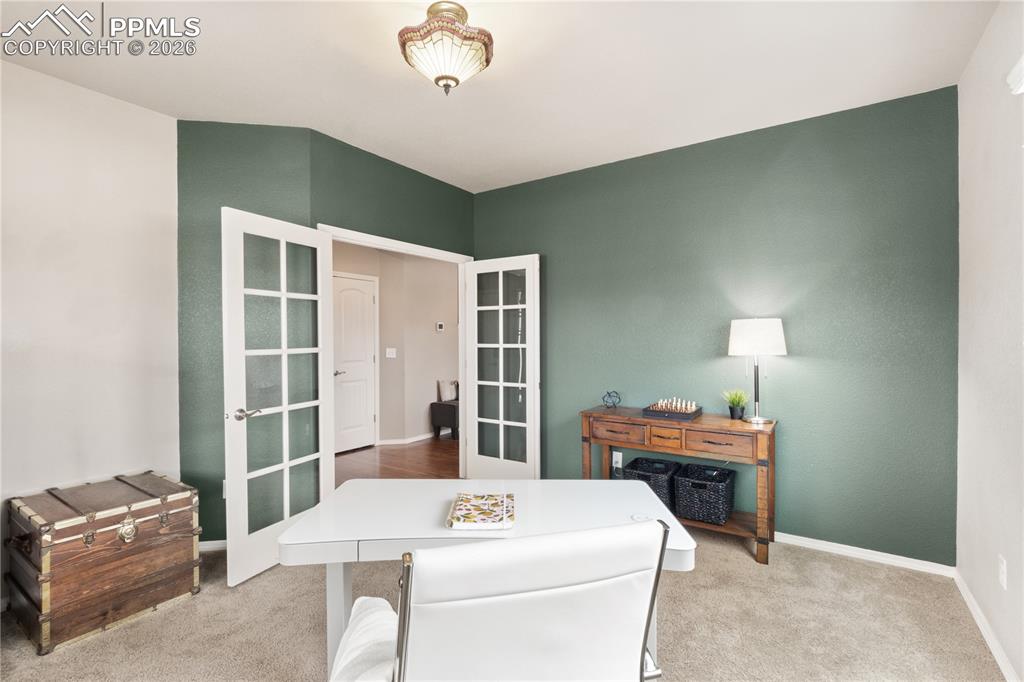 Image 11 of 50: Office space with light colored carpet and french doors