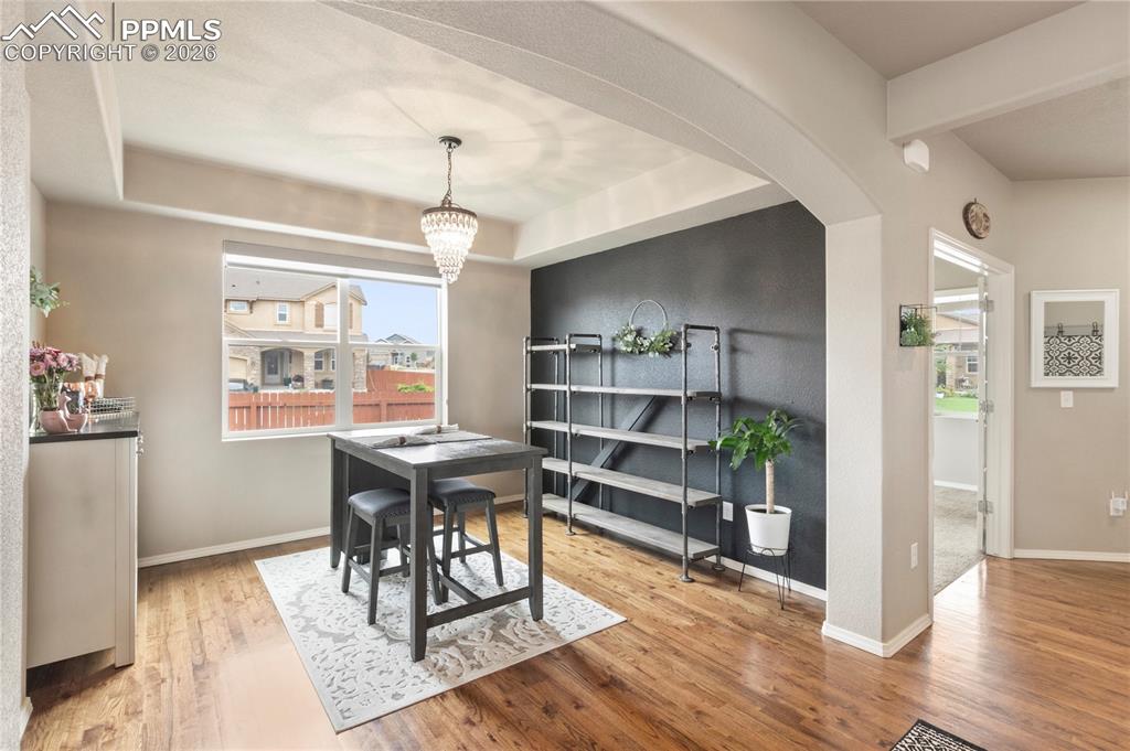 Image 13 of 50: Dining area with light wood-type flooring, a tray ceiling, a chandelier, ar