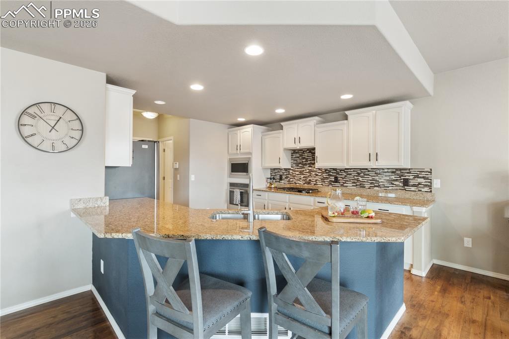 Image 19 of 50: Kitchen featuring a peninsula, a kitchen breakfast bar, white cabinets, lig