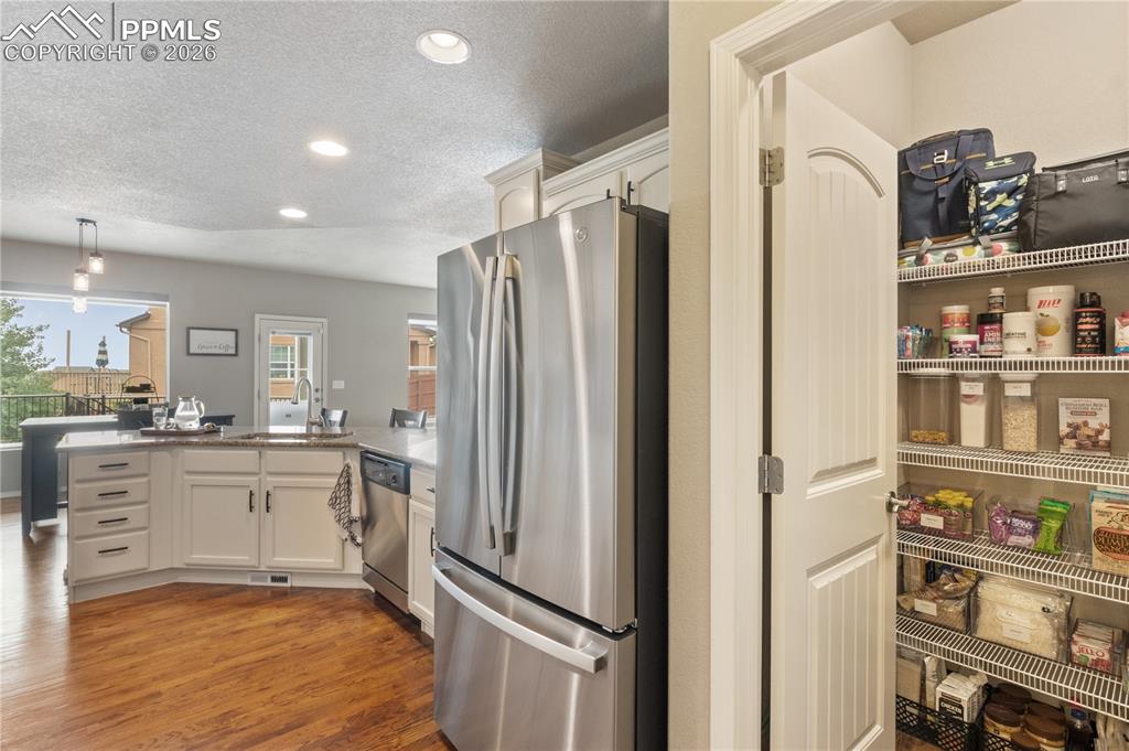 Image 21 of 50: Kitchen with stainless steel appliances, a peninsula, a textured ceiling, w