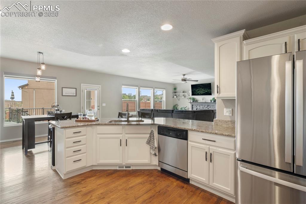 Image 22 of 50: Kitchen with stainless steel appliances, a peninsula, white cabinetry, ligh