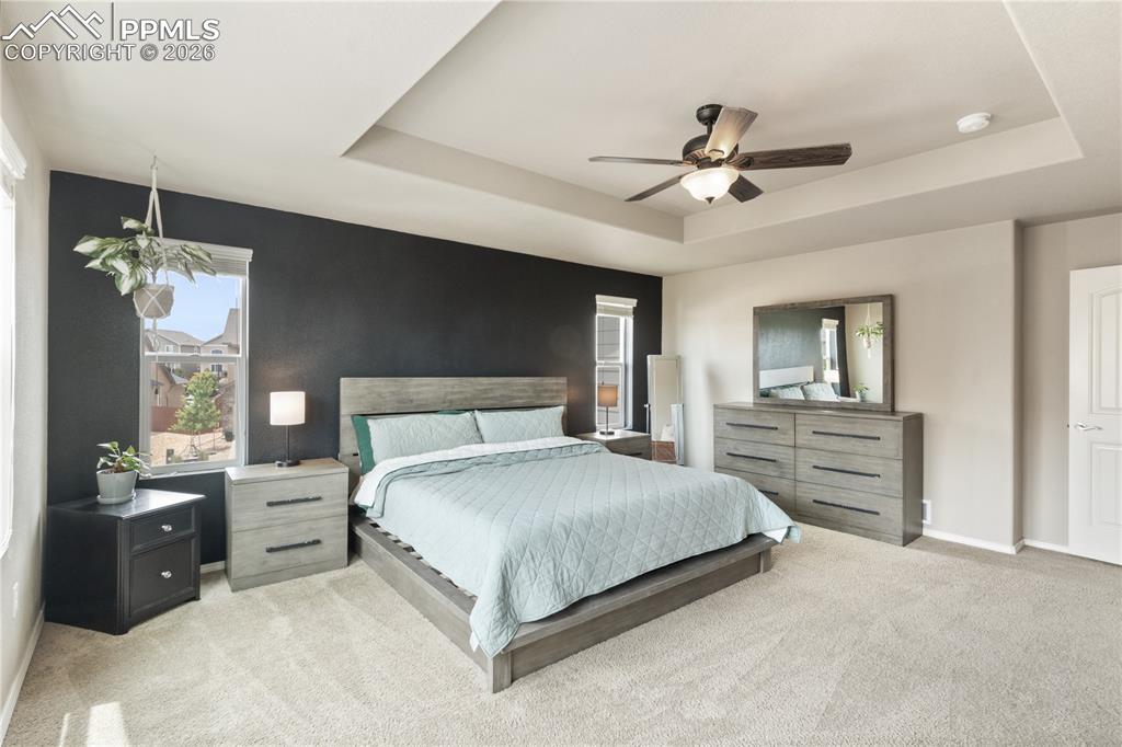 Image 25 of 50: Bedroom featuring light carpet, a ceiling fan, and a raised ceiling