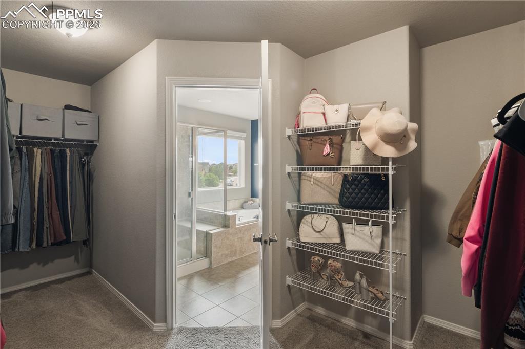 Image 29 of 50: Walk in closet with light colored carpet and light tile patterned floors