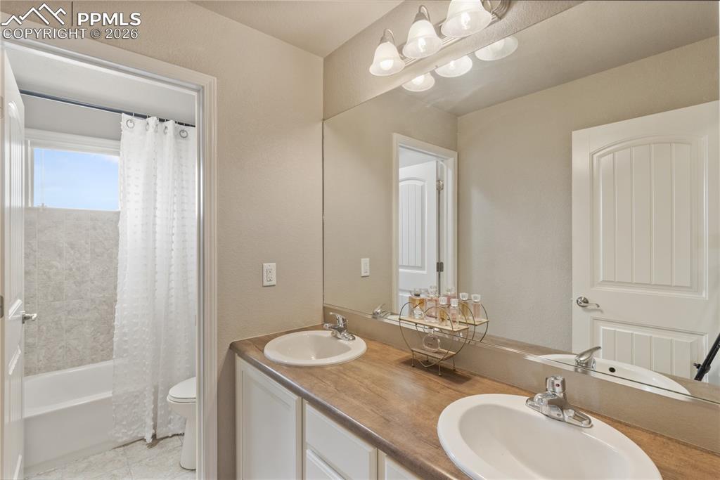 Image 35 of 50: Bathroom with double vanity and shower / bath combination with curtain