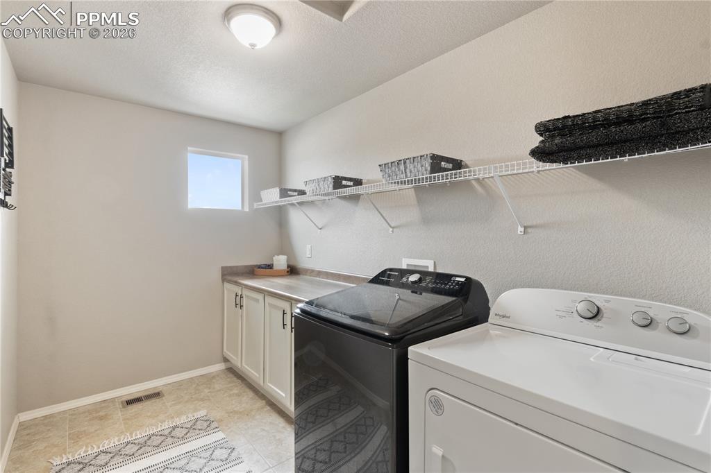 Image 36 of 50: Laundry room featuring washing machine and clothes dryer, a textured ceilin