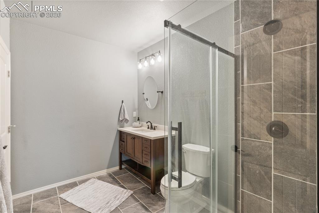 Image 44 of 50: Bathroom featuring a stall shower, vanity, and dark tile patterned floors