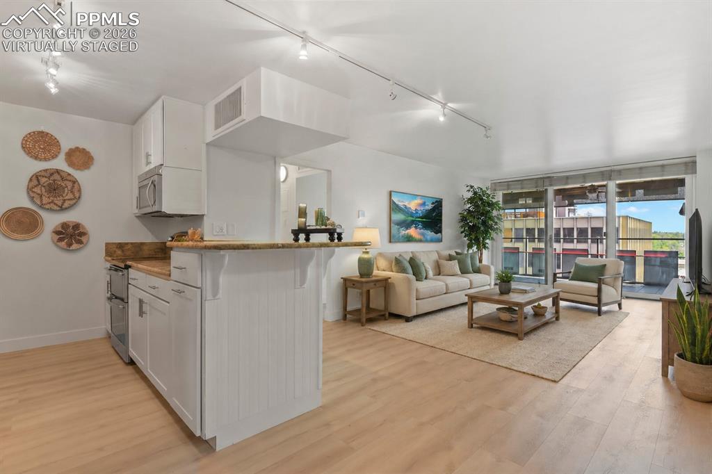Image 4 of 30: virtually staged view with kitchen and living room