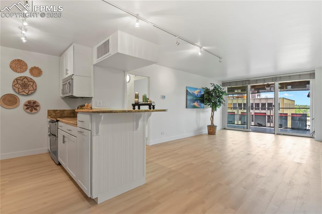Image 5 of 30: This kitchen and living room is bright with light