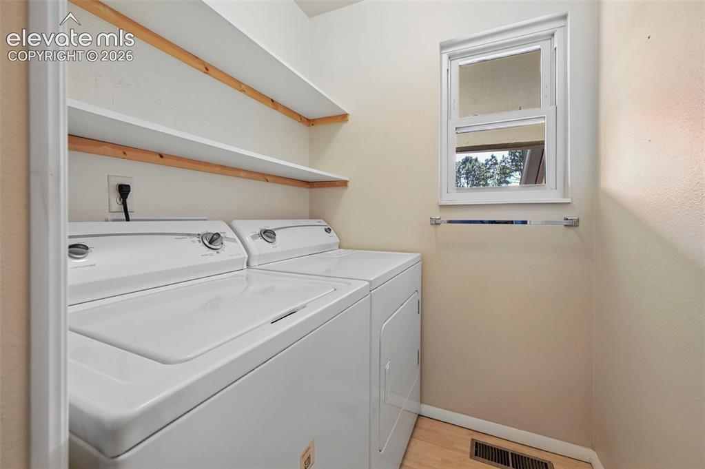 Image 13 of 24: Laundry area featuring wood-finish flooring and multiple built-in shelves