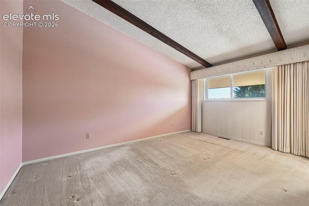 Image 15 of 24: Large primary bedroom with exposed wood beams