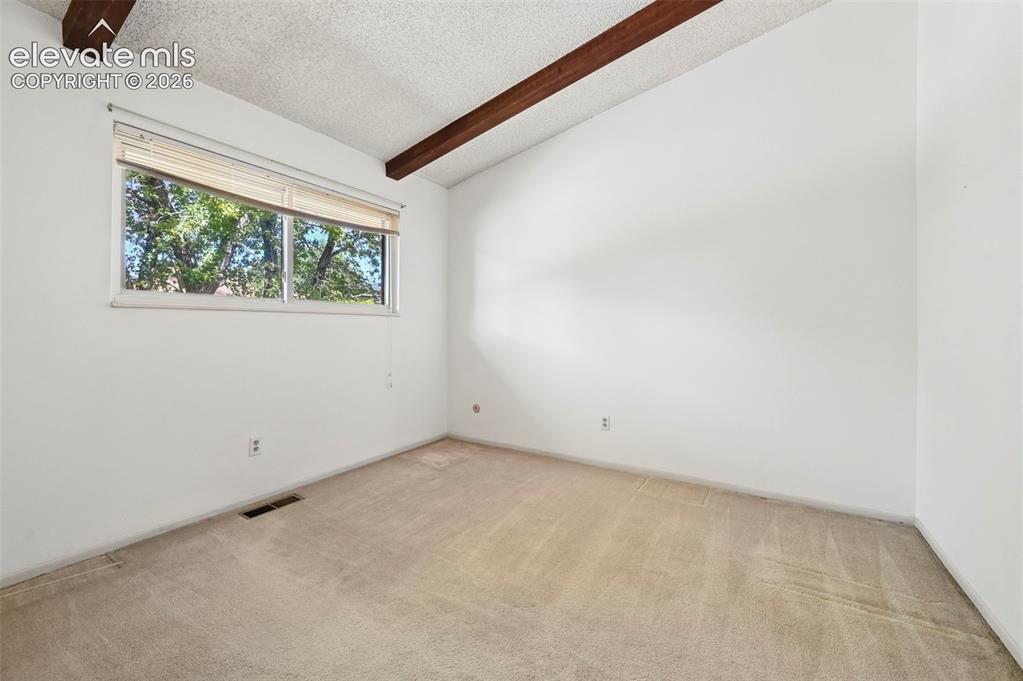 Image 19 of 24: Vaulted ceiling with exposed wood beams, wall-to-wall carpeting, and a doub