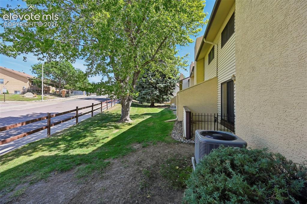 Image 3 of 24: End unit with mature landscaping, split rail fencing, and established trees