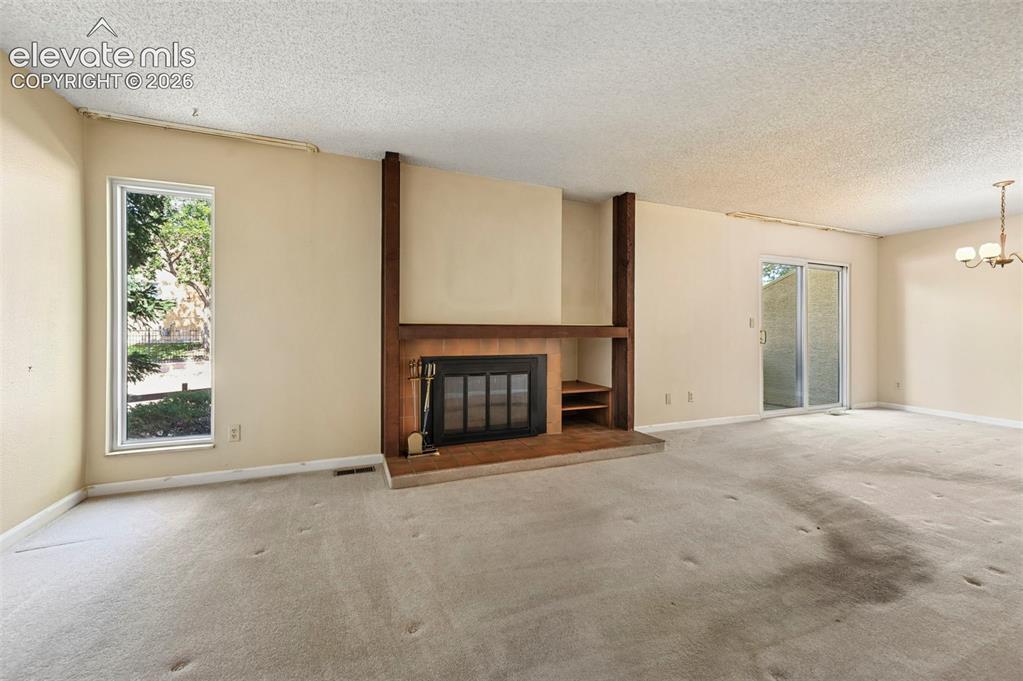 Image 5 of 24: Large, bright living room with built-in fireplace with wood-finish mantel a