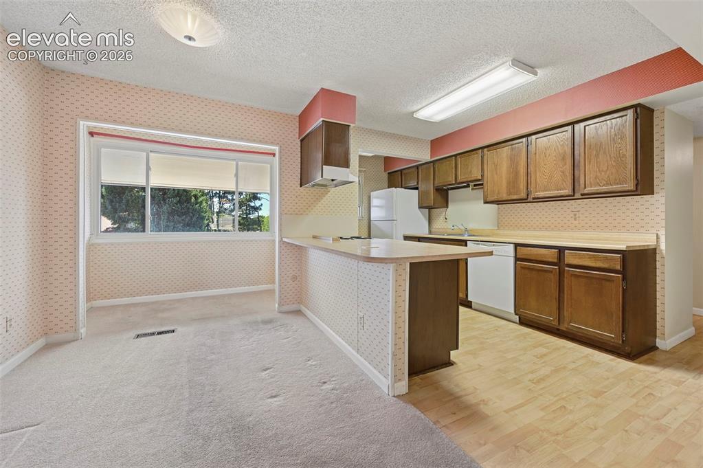 Image 8 of 24: Kitchen with wood-finish flooring, wood cabinetry, and a breakfast bar