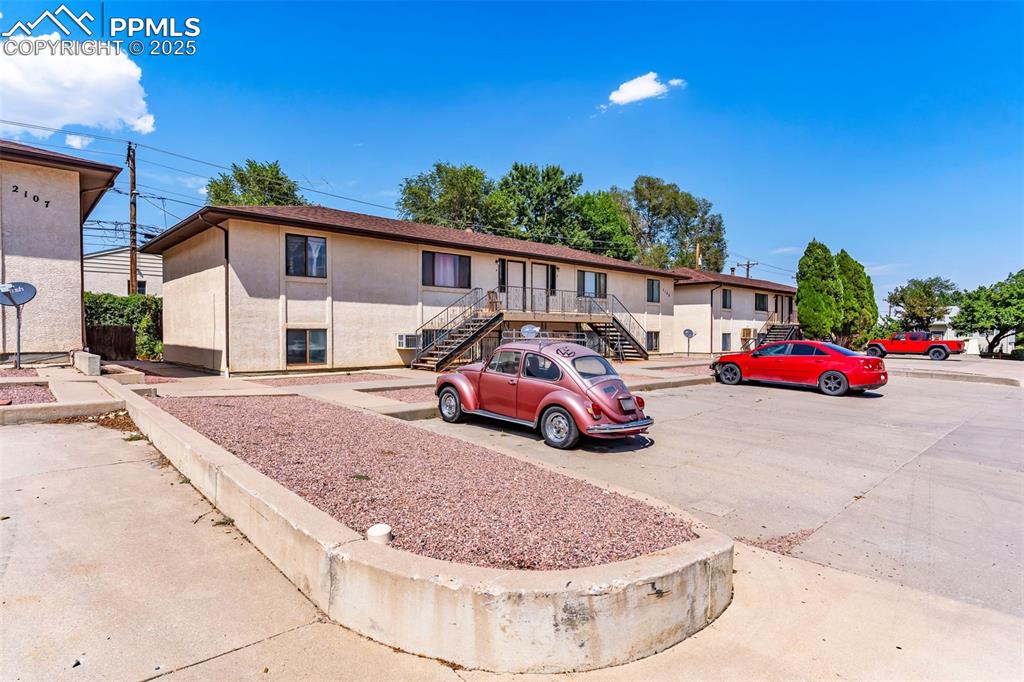 Image 10 of 26: View of front of property with stairway, stucco siding, and uncovered parki