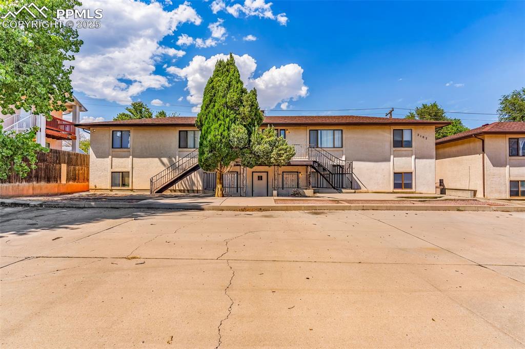 Image 11 of 26: View of front of property with stairs, stucco siding, and a patio