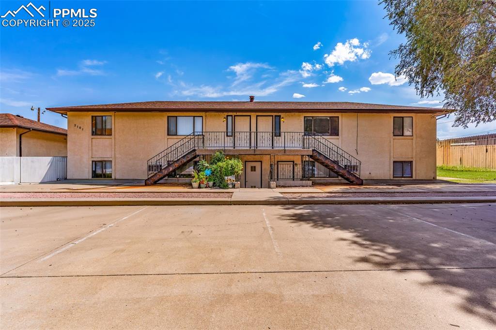 Image 12 of 26: View of front of property with stairway, stucco siding, uncovered parking, 