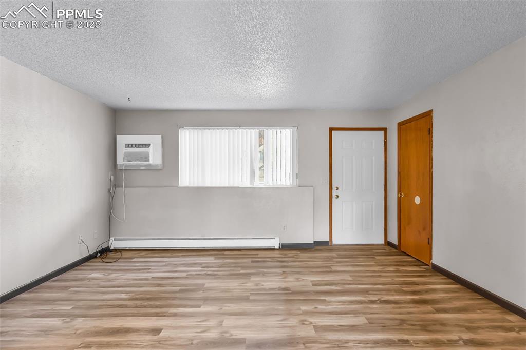 Image 14 of 26: Empty room featuring light wood-style flooring, a textured ceiling, baseboa