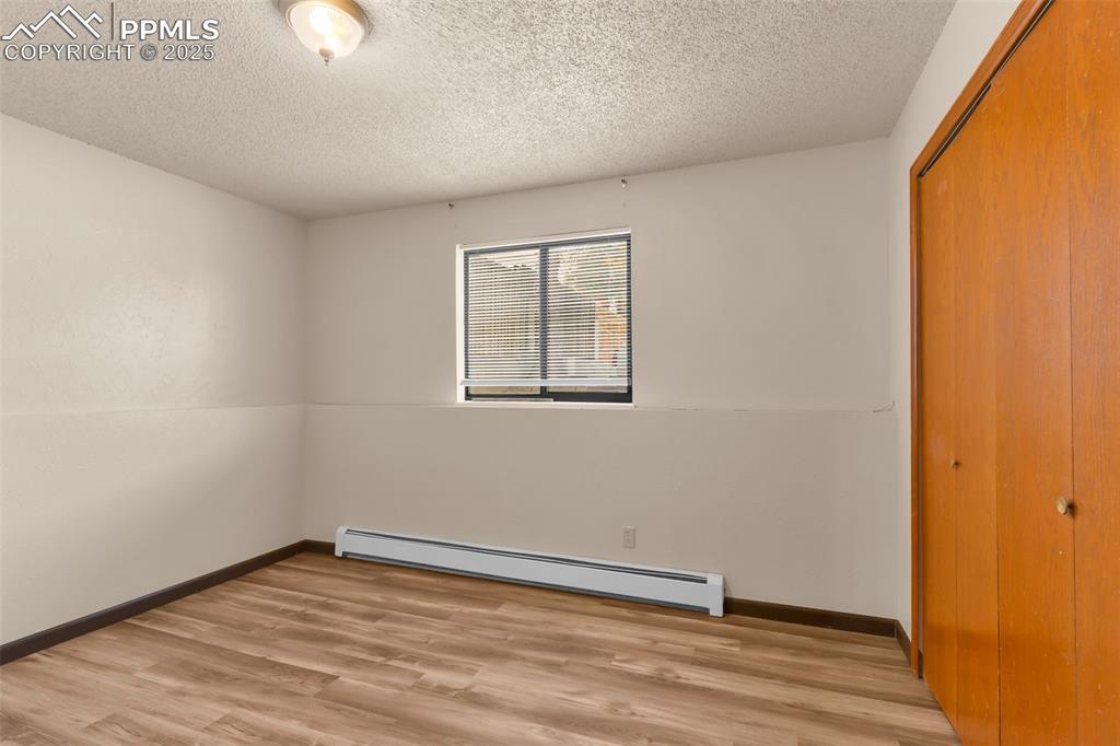 Image 22 of 26: Unfurnished bedroom featuring baseboard heating, light wood finished floors