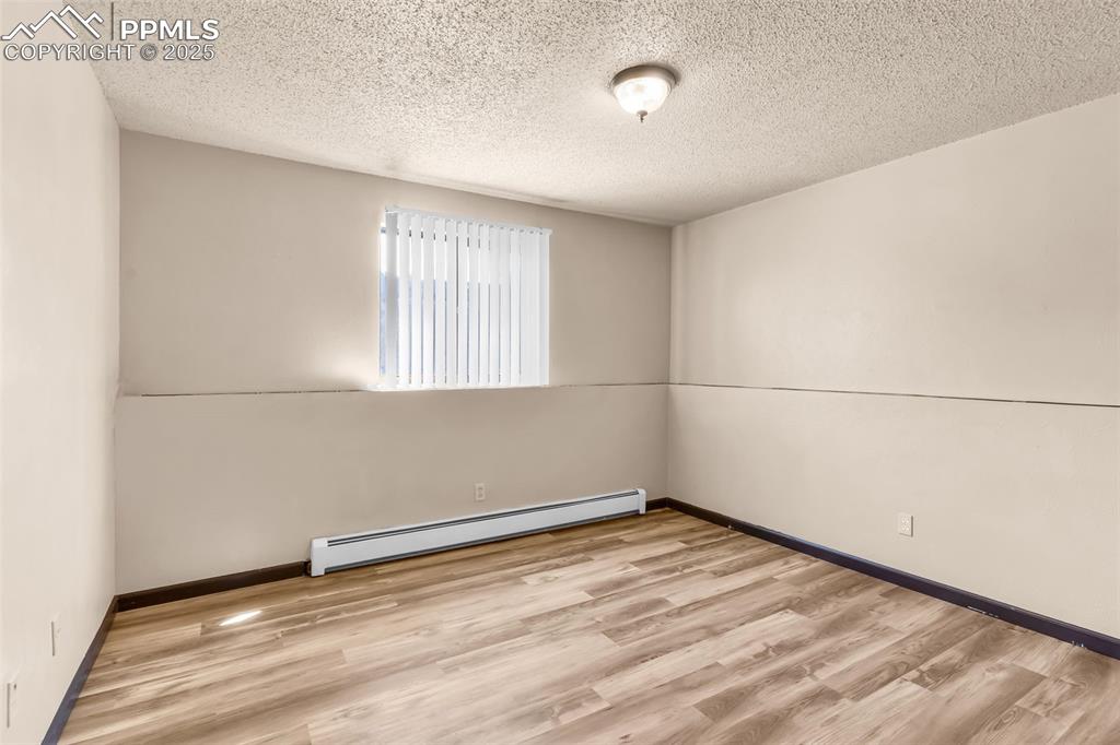 Image 24 of 26: Spare room featuring baseboard heating, light wood-style floors, and a text