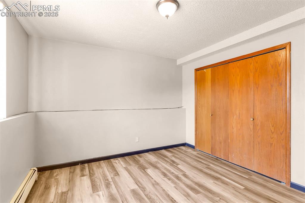 Image 25 of 26: Unfurnished bedroom with a baseboard radiator, light wood finished floors,