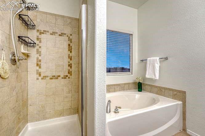 Image 24 of 44: Primary bathroom with soaking tub and shower.