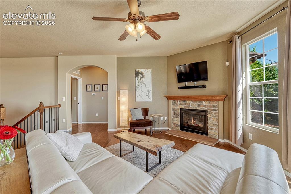Image 15 of 50: Living room features a cozy fireplace with stone surround