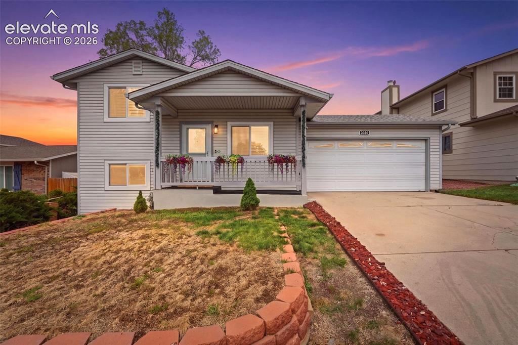 Image 1 of 45: Split-level residence featuring light-colored siding, an attached two-car g