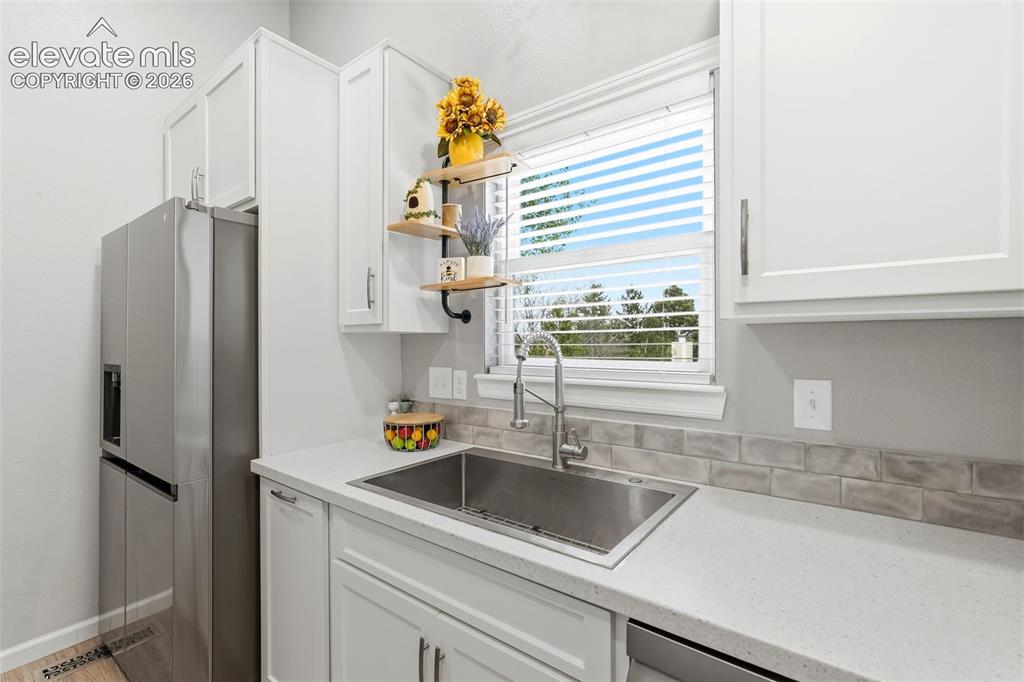 Image 11 of 45: Kitchen featuring white shaker-style cabinetry, a stainless steel sink with