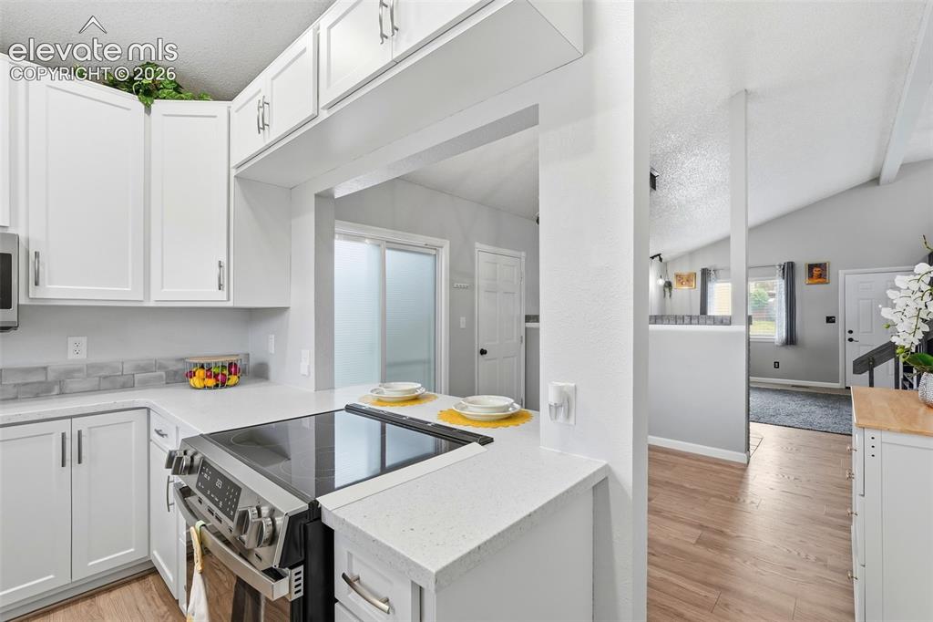 Image 13 of 45: Kitchen with white shaker cabinetry, light-toned countertops, tile backspla