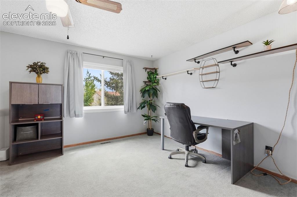 Image 15 of 45: Carpeted room featuring a large window, neutral gray walls, a ceiling fan,