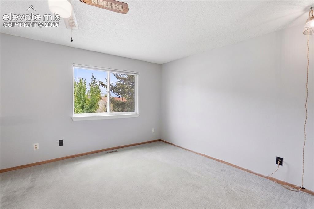 Image 15 of 45: Carpeted room featuring a large window, neutral gray walls, a ceiling fan,