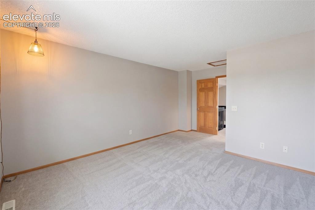 Image 18 of 45: Carpeted room featuring light gray walls, white trim, and a warm wood-panel