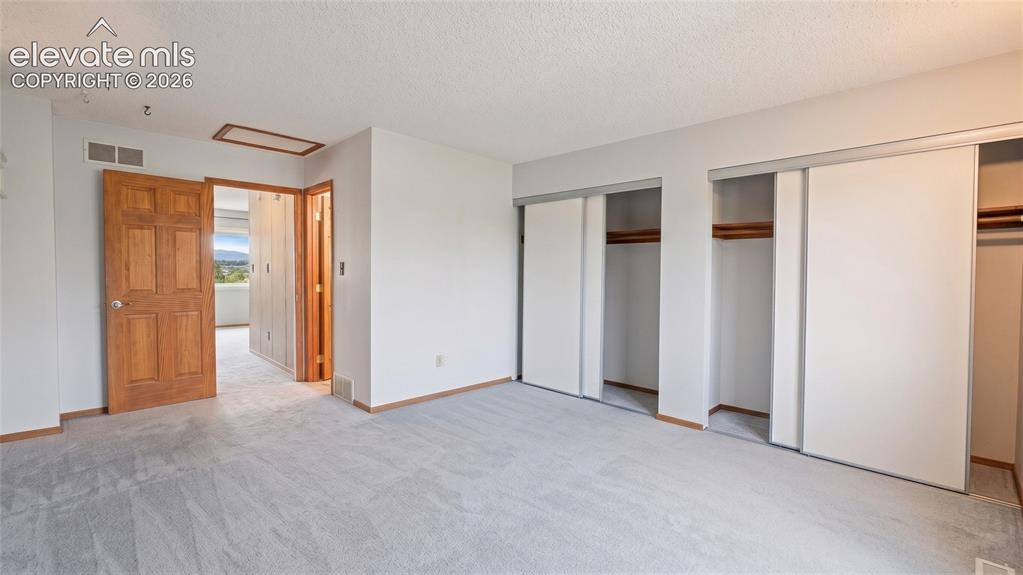 Image 19 of 45: Carpeted room featuring multiple sliding door closets, a six-panel wood doo
