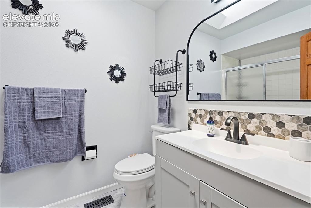 Image 20 of 45: Bathroom featuring a white vanity with integrated sink, a hexagon tile back