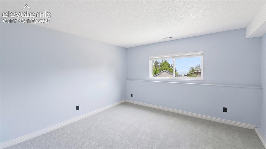 Image 22 of 45: Spacious room with light blue walls, white trim, and light gray carpeting