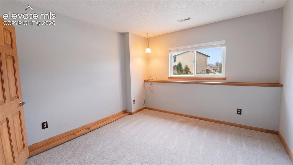 Image 24 of 45: Carpeted room with a horizontal window featuring a wood-finish sill and tri