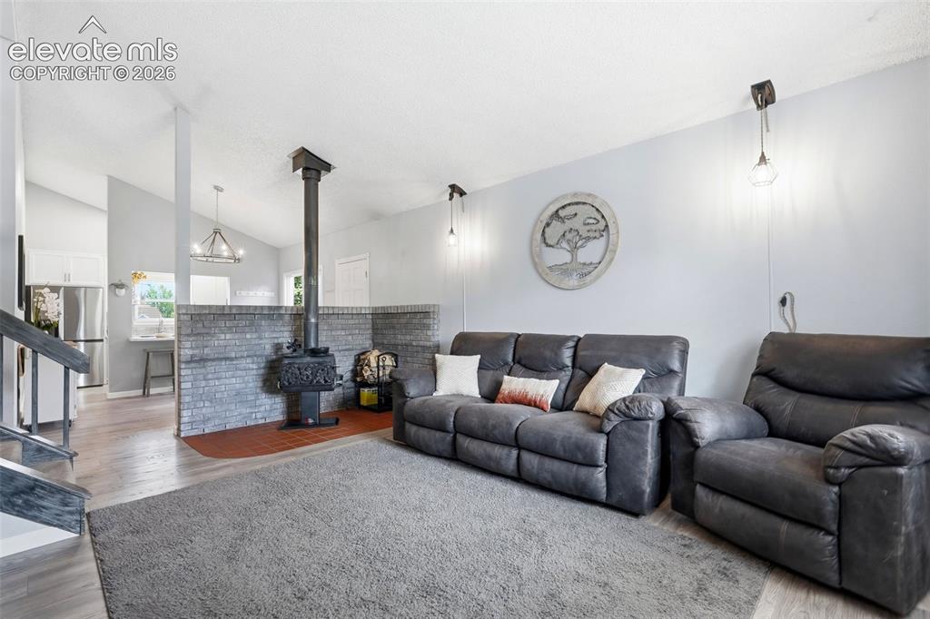 Image 3 of 45: Living area featuring a freestanding wood-burning stove with a brick half-w
