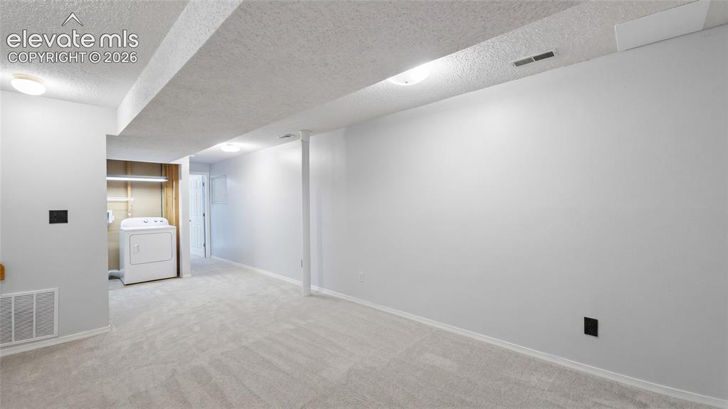 Image 30 of 45: Spacious lower-level area featuring light gray carpeting and freshly painte