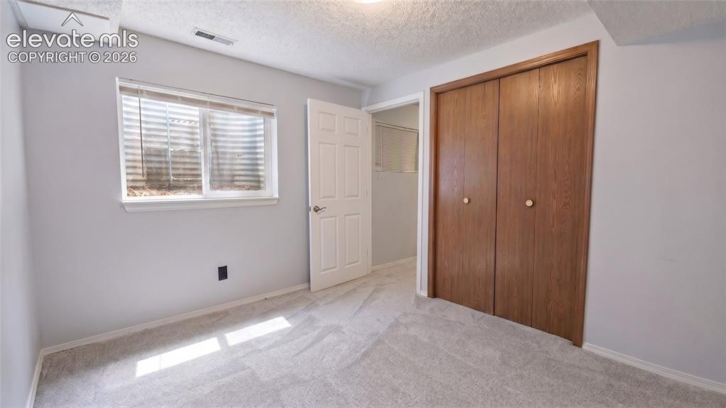 Image 32 of 45: Carpeted basement bedroom with a window, white trim, and a wood-finish bi-f