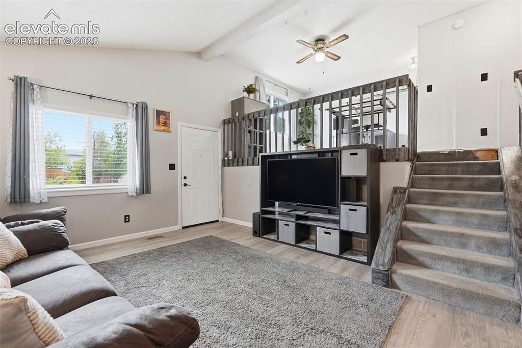 Image 5 of 45: Living area featuring wood-finish flooring, a vaulted ceiling with exposed