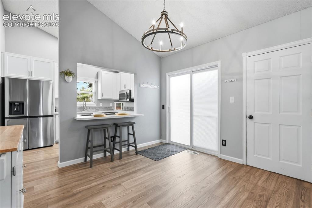 Image 8 of 45: Dining area featuring wood-finish flooring and a contemporary chandelier