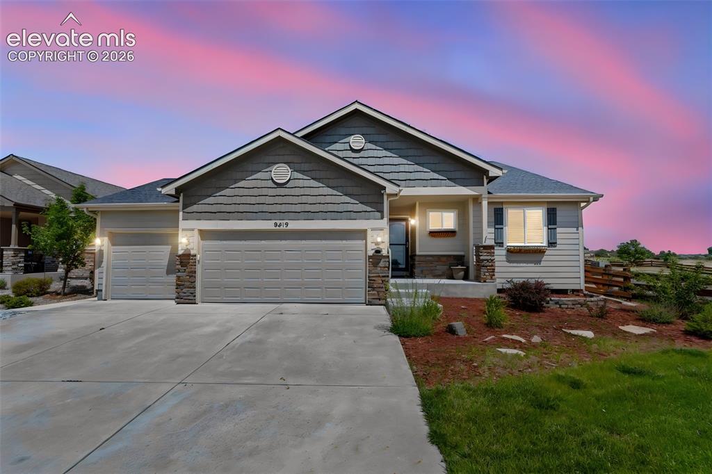 Caption: Siding exterior with decorative stone accents, two-car garage, concrete driveway, and front landscap