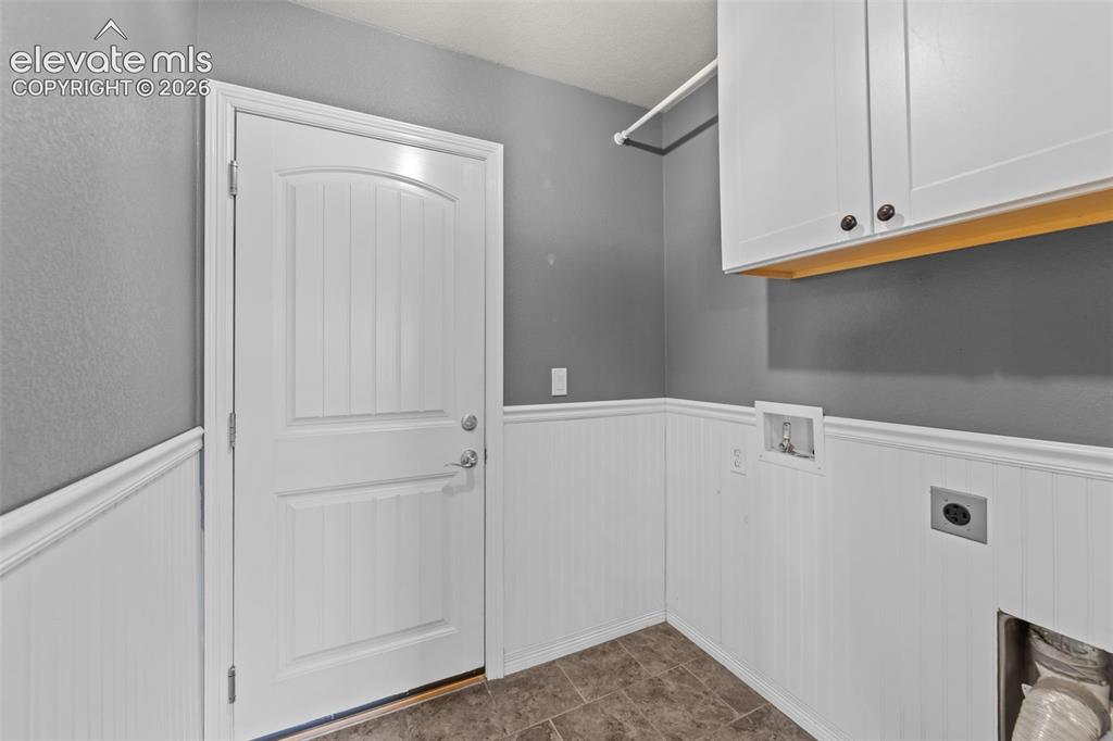 Image 16 of 40: White wainscoting with decorative trim, durable flooring, white storage cab