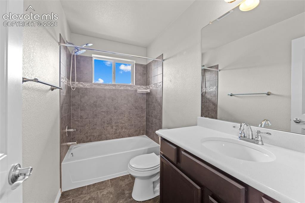 Image 19 of 40: Bathroom featuring a shower/tub combination with tiled surround, a window p