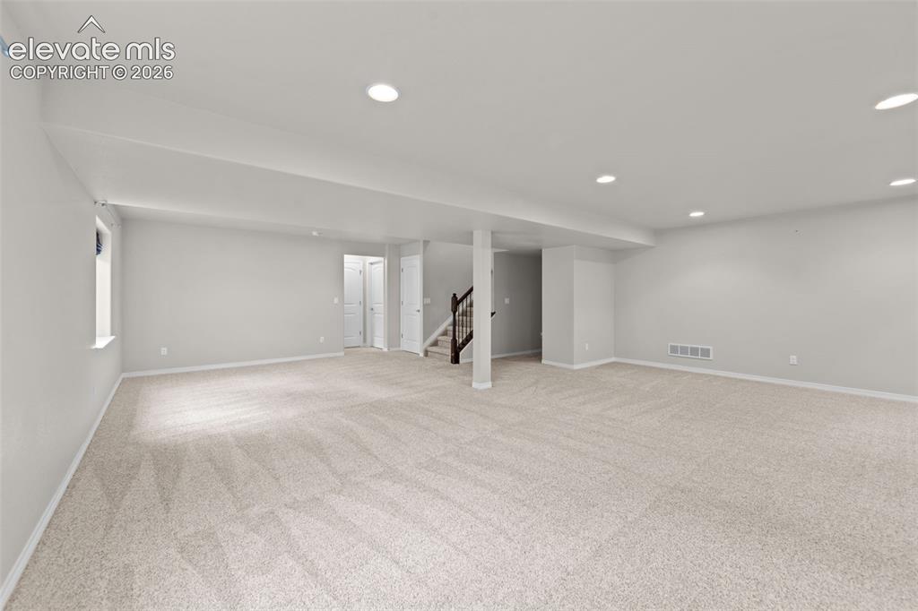 Image 21 of 40: Expansive open room featuring plush carpeting, recessed lighting, and a neu