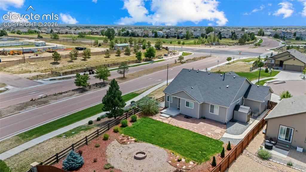 Image 32 of 40: Manicured lawn with a fire pit area, surrounded by a wooden fence