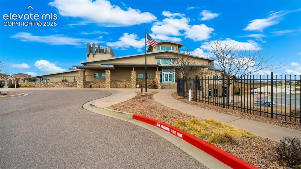 Image 38 of 40: Stone facade building with a curved driveway, paved walkway, and landscapin