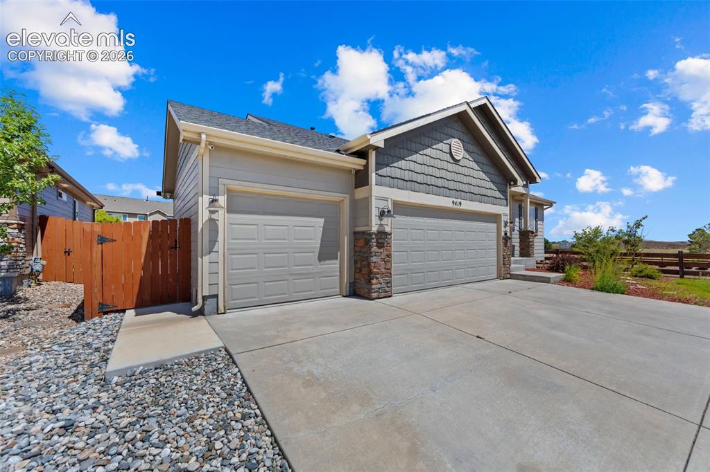 Image 5 of 40: Concrete driveway with integrated walkway, two-car garage, and stone accent